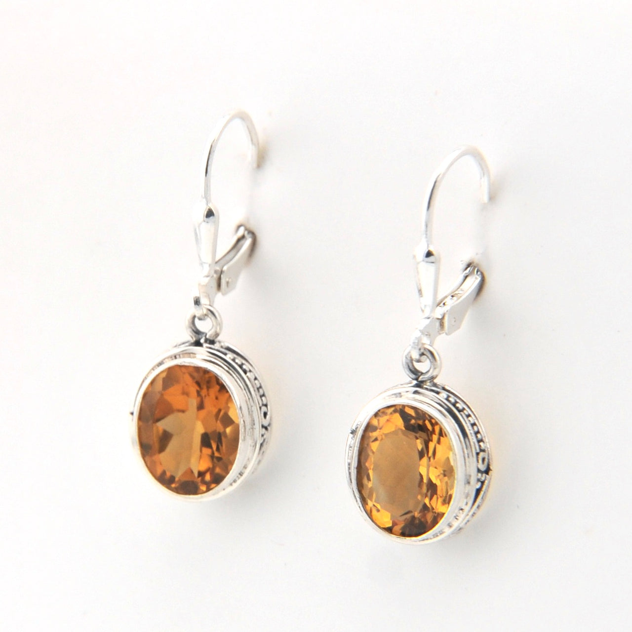 Pair of silver earrings with amber-colored stones on a white background