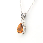 Teardrop-shaped citrine pendant on a silver chain against a white background