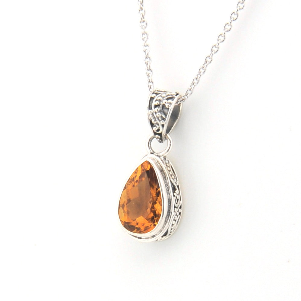 Teardrop-shaped citrine pendant on a silver chain against a white background
