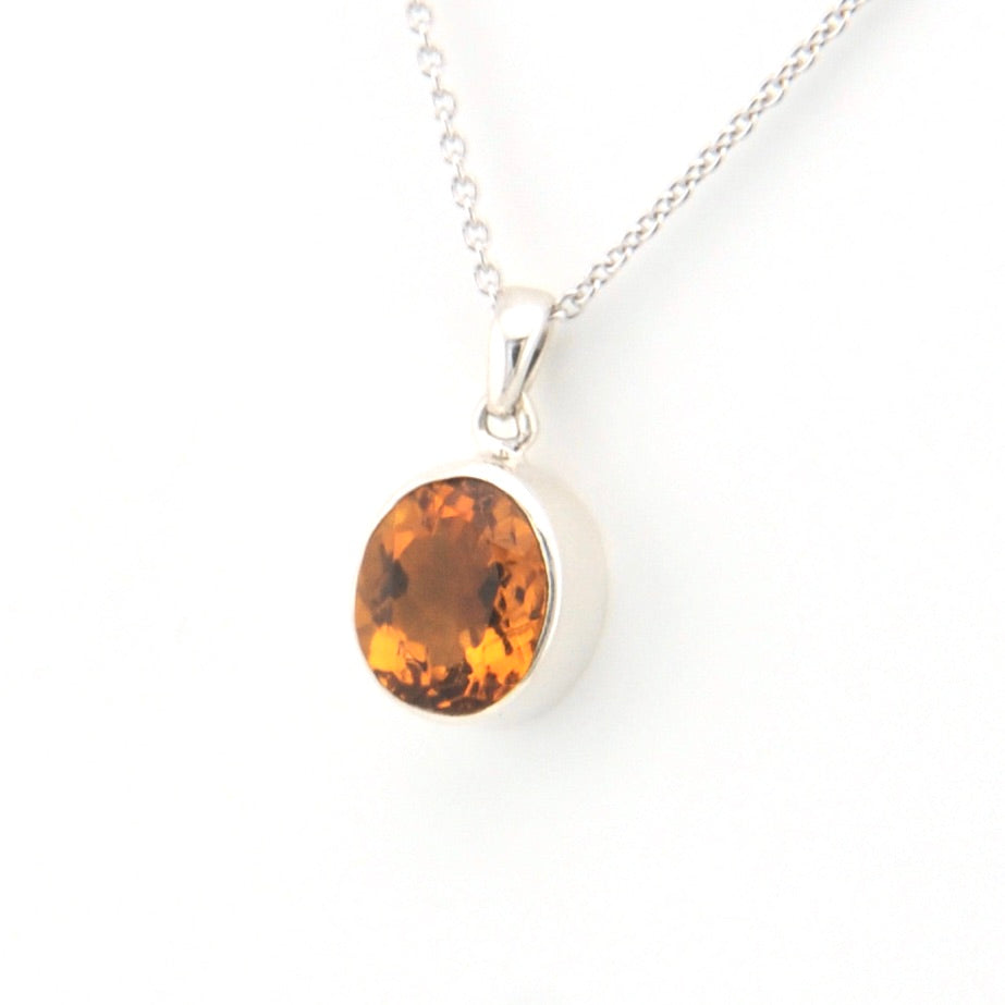 Silver necklace with a round citrine pendant on a white background