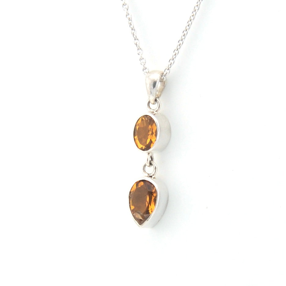 Silver necklace with two teardrop-shaped citrine stones on a white background