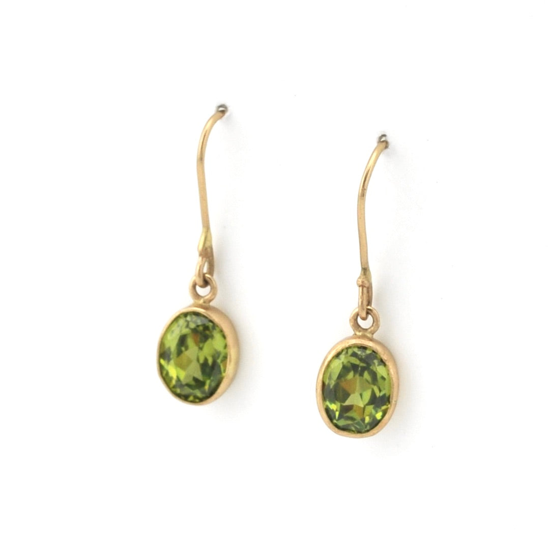 Gold earrings with green gemstones on a white background