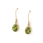Gold earrings with green gemstones on a white background
