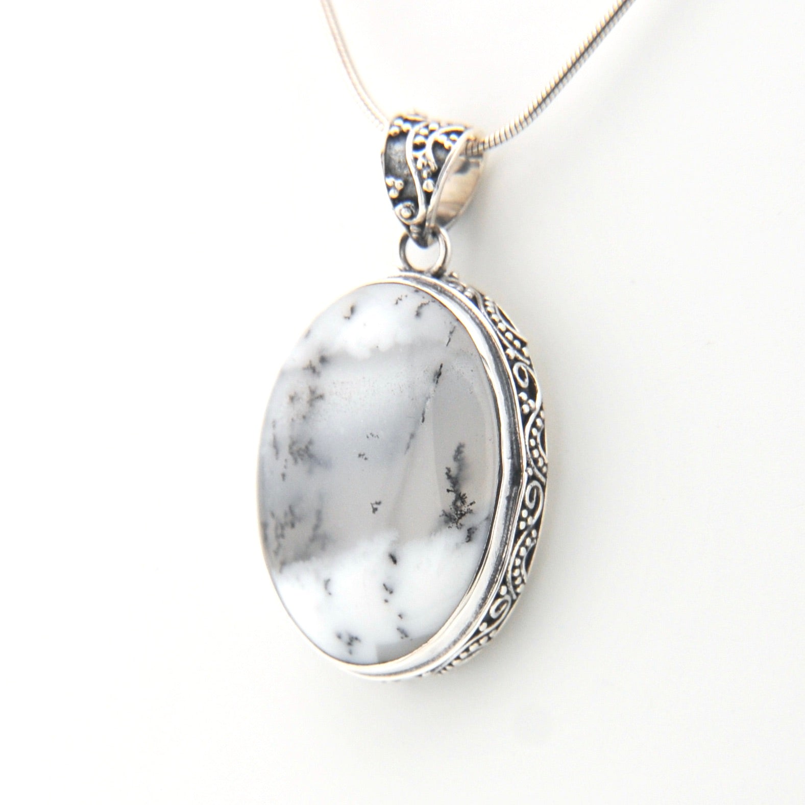 Silver pendant with a white stone on a white background