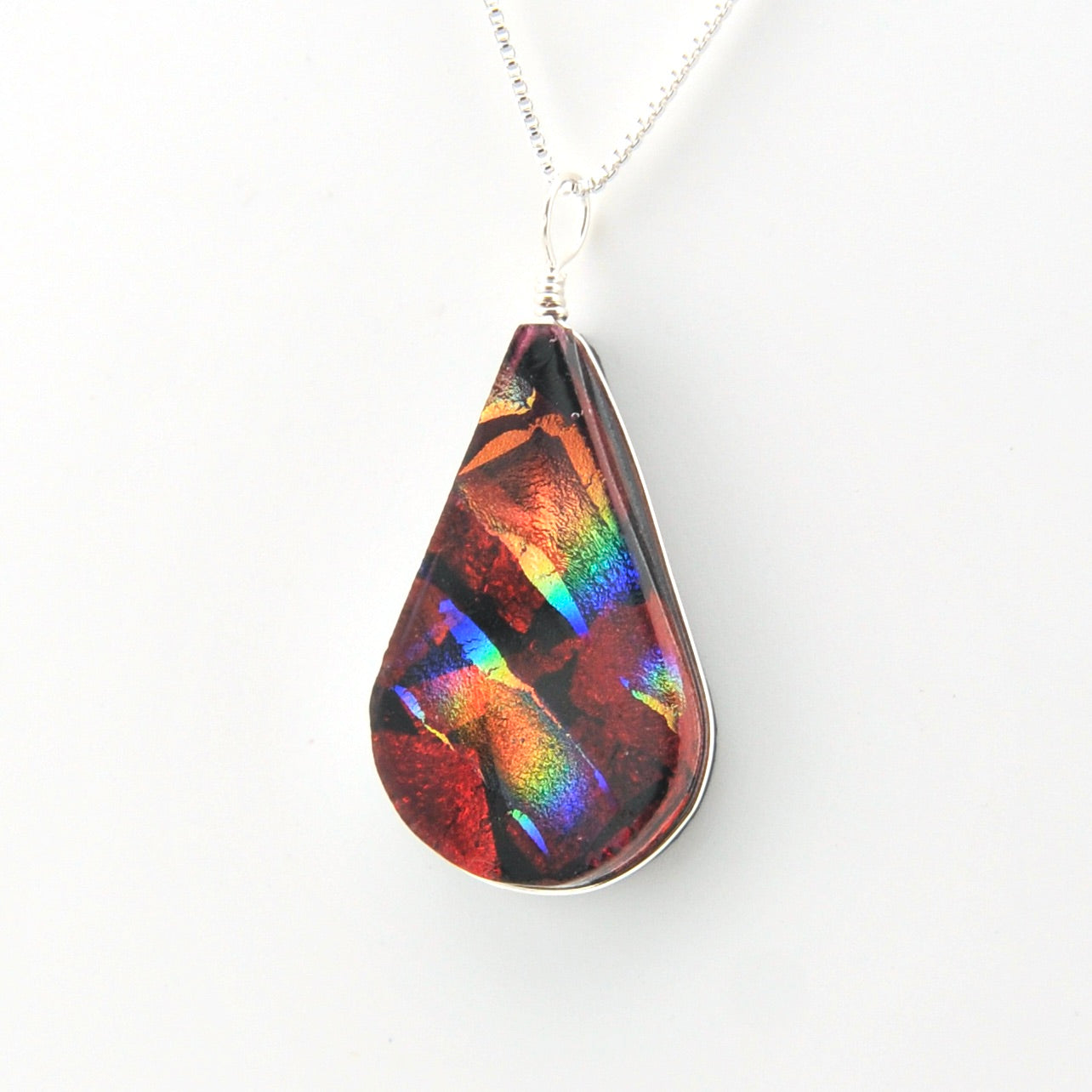 Teardrop-shaped pendant with multicolored iridescent finish on a white background
