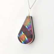 Teardrop-shaped pendant with multicolored iridescent surface on a white background