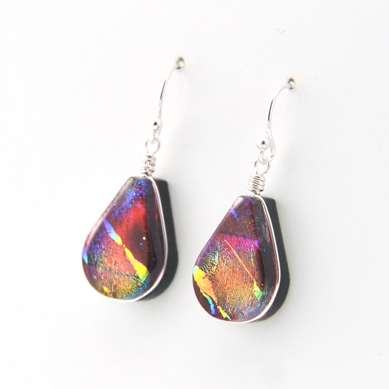 Teardrop-shaped earrings with multicolored iridescent finish on a white background