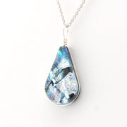 Teardrop-shaped pendant with a blue and silver design on a white background