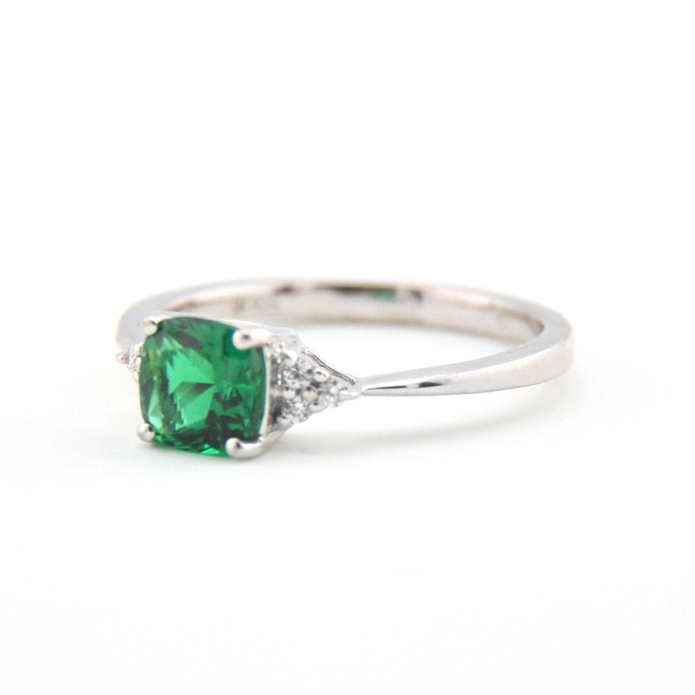 Silver ring with a green gemstone on a white background