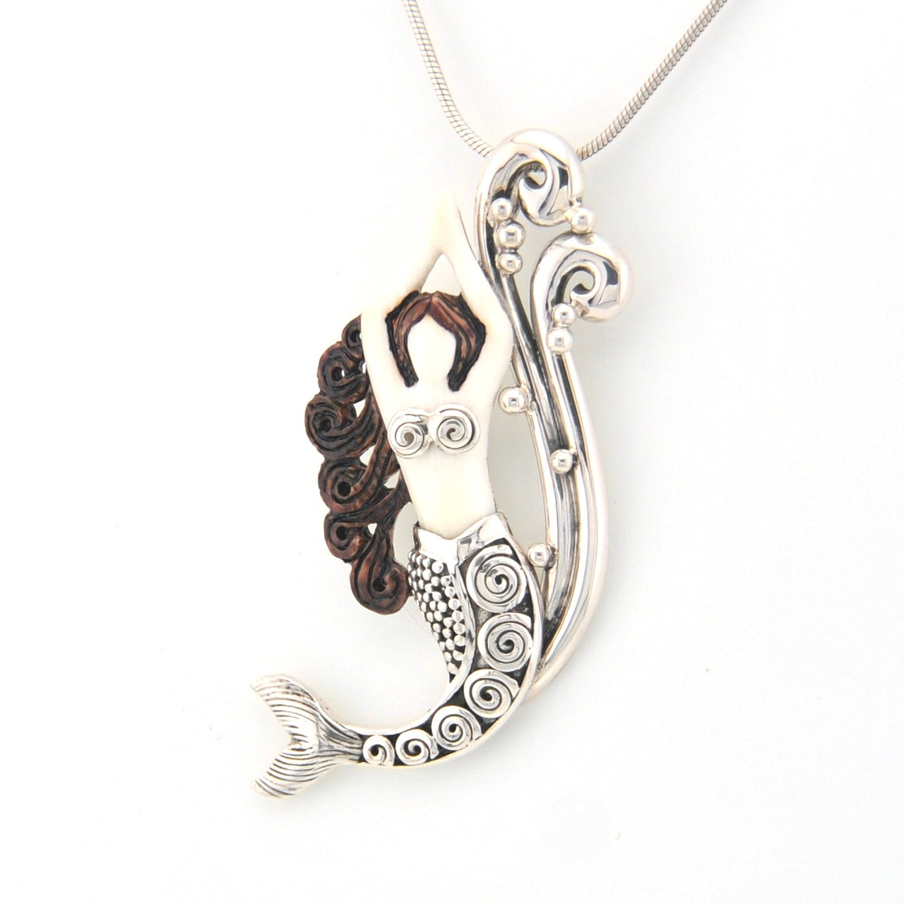 Silver and bronze mermaid pendant on a white background