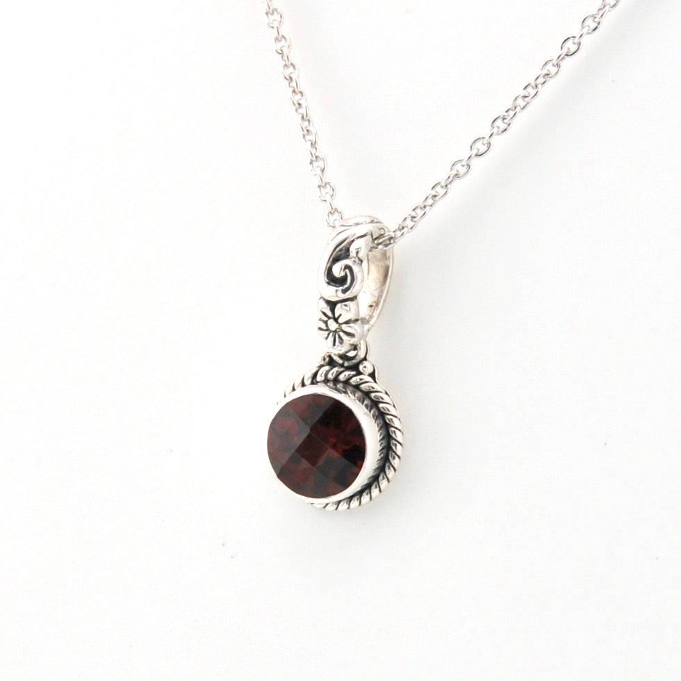 Silver necklace with a garnet pendant on a white background