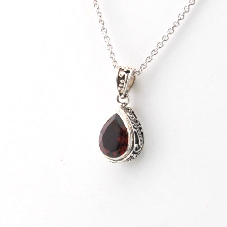 Silver pendant with a red gemstone on a white background