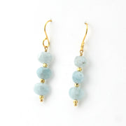 Pair of earrings with light blue beads and gold accents on a white background