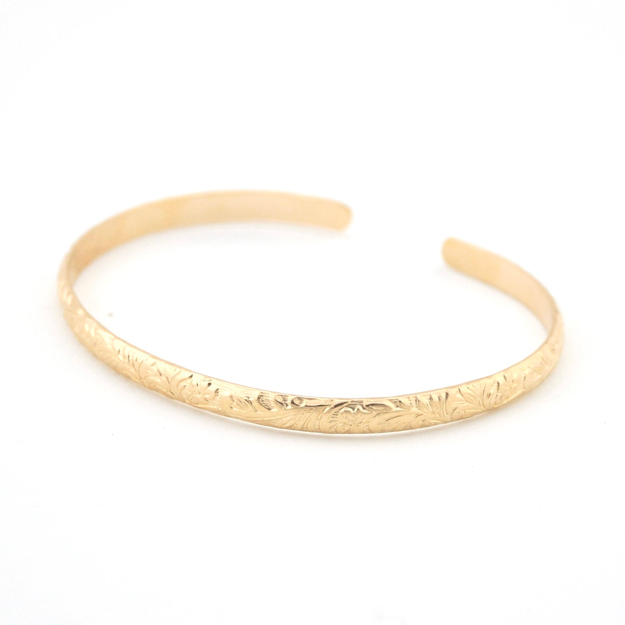 Gold bracelet with engraved design on a white background