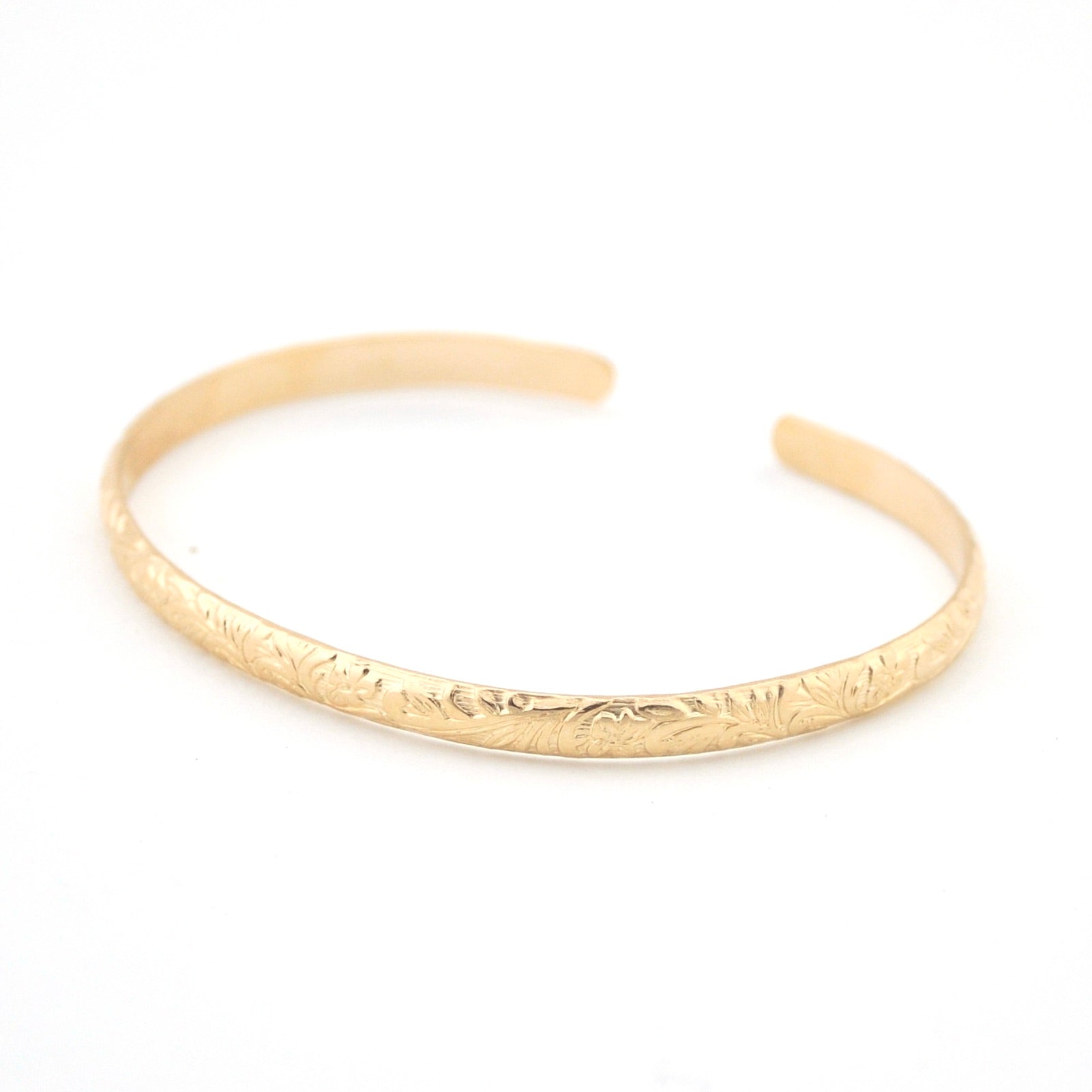 Gold bracelet with engraved design on a white background