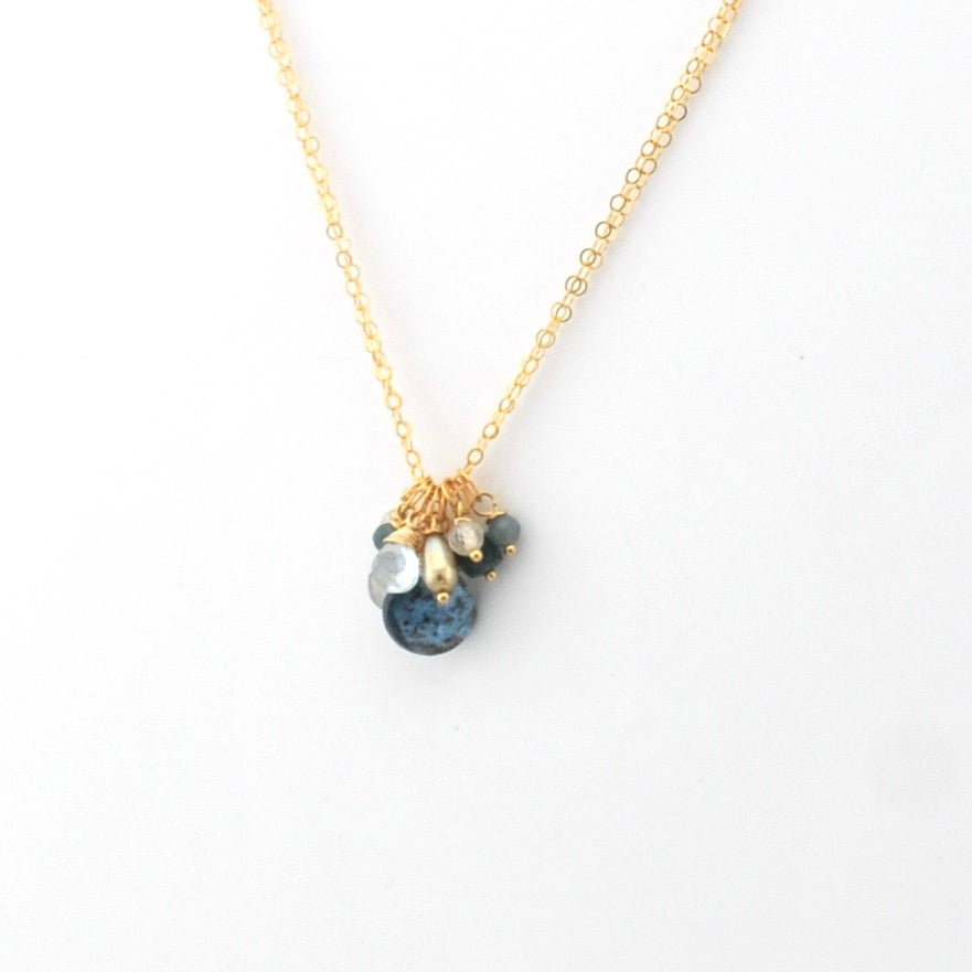 Gold necklace with blue and white bead charms on a white background