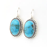 Turquoise oval earrings with silver detailing on a white background