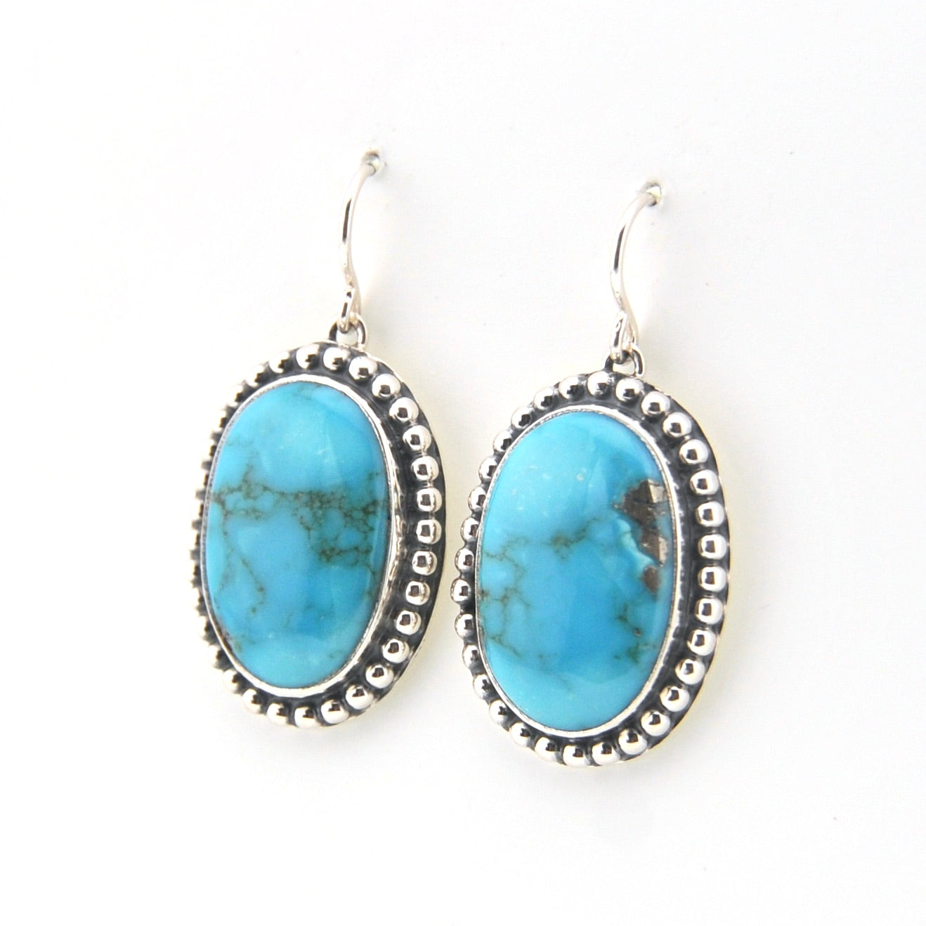 Turquoise oval earrings with silver detailing on a white background