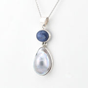 Silver pendant with a teardrop-shaped pearl and blue stone on a white background
