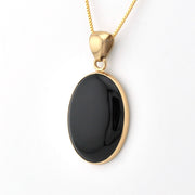 Gold necklace with a black pendant on a white background
