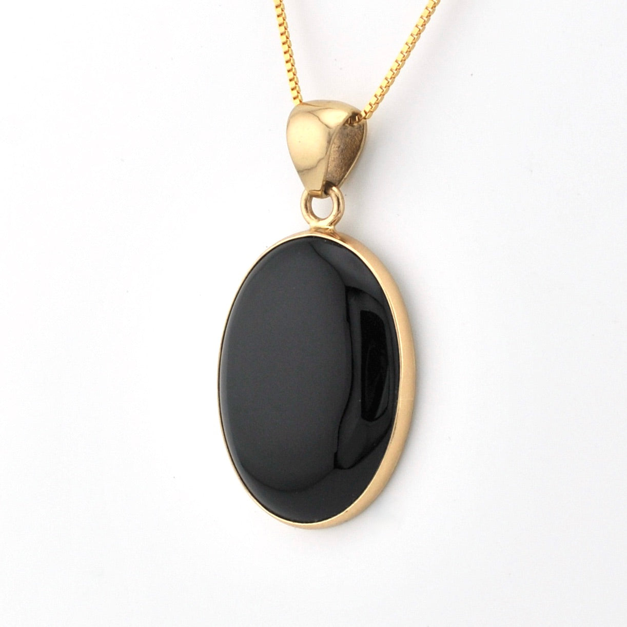 Gold necklace with a black pendant on a white background