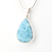 Teardrop-shaped larimar pendant on a silver chain against a white background