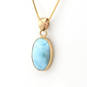 Gold necklace with a blue pendant on a white background