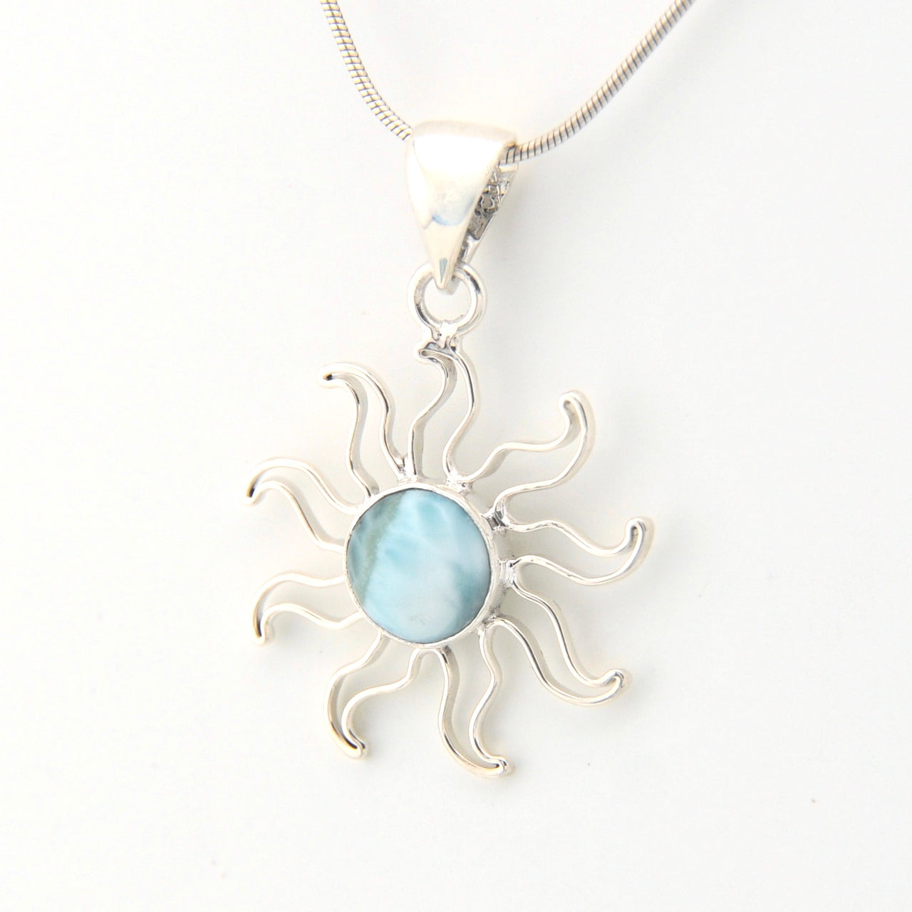Silver sun-shaped pendant with a blue gemstone on a white background