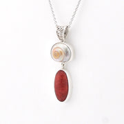 Necklace with a shell pendant and red stone on a white background