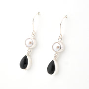 Pair of earrings with black teardrop and pearl elements on a white background