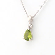 Silver necklace with a green teardrop pendant on a white background