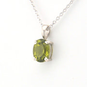 Silver pendant with a green gemstone on a white background
