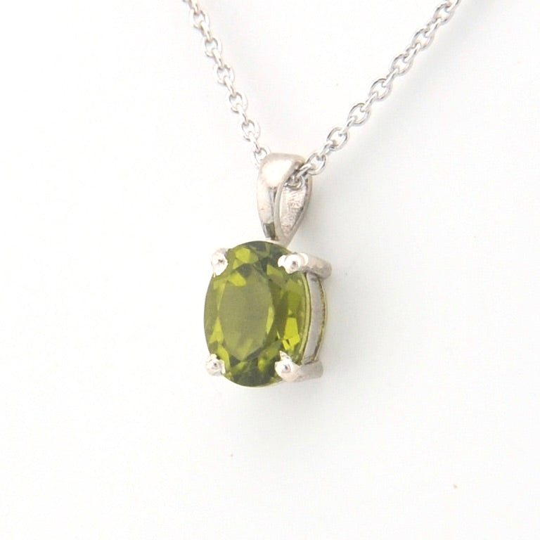 Silver pendant with a green gemstone on a white background