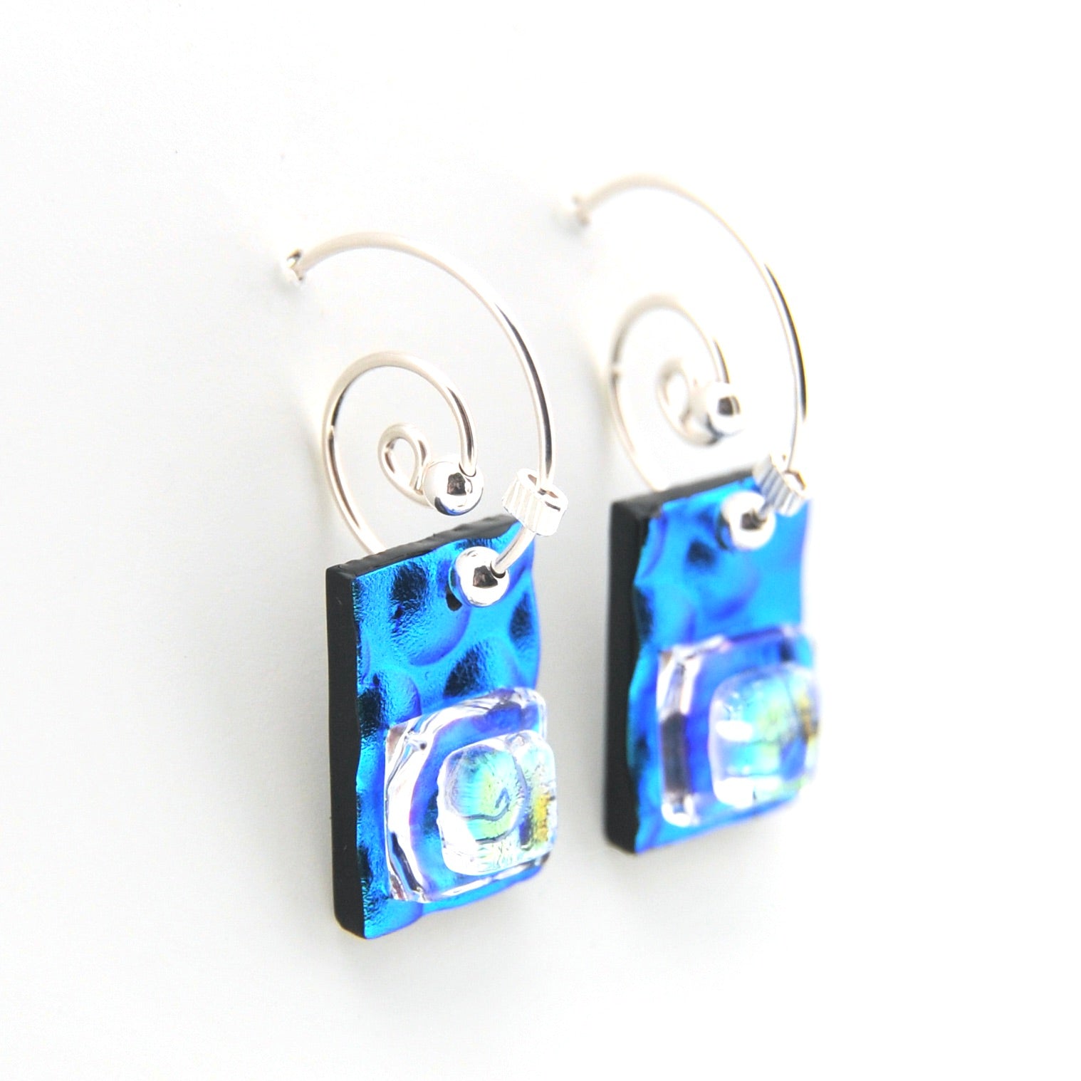 Blue glass earrings on silver hooks against a white background