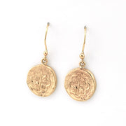 Gold coin-shaped earrings on a white background