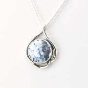 Silver pendant with a blue gemstone on a white background