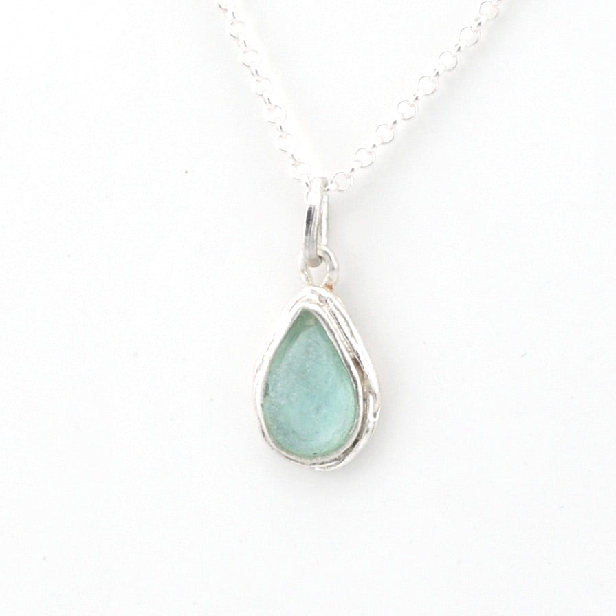 Teardrop-shaped pendant with a light blue Roman glass on a white background