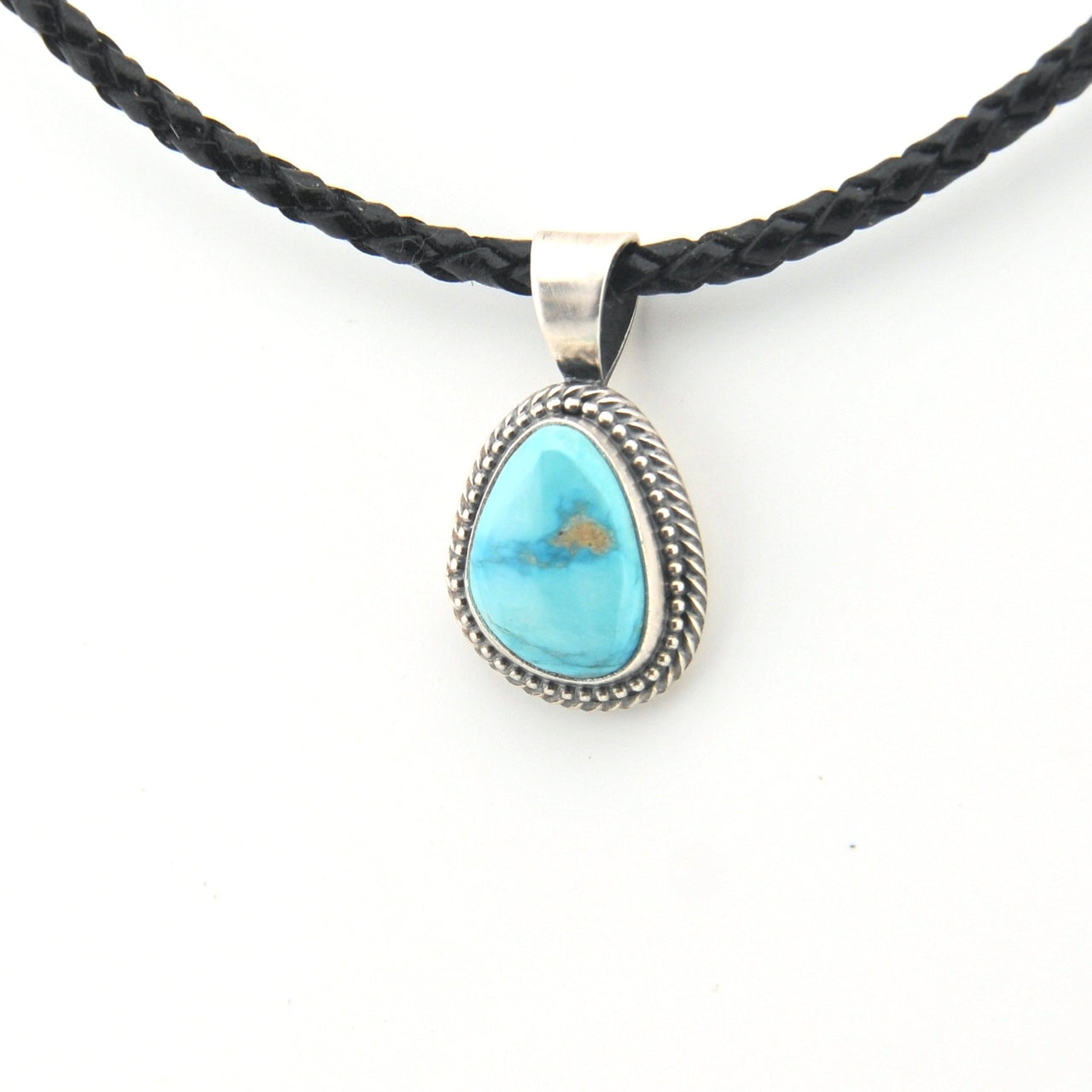 Turquoise pendant on a braided black cord against a white background