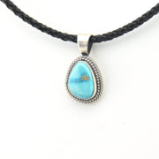 Turquoise pendant on a braided black cord against a white background