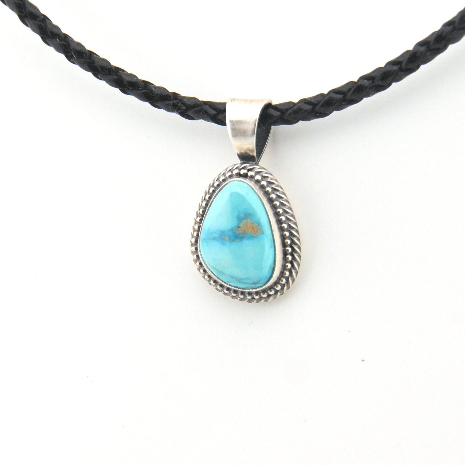 Turquoise pendant on a braided black cord against a white background