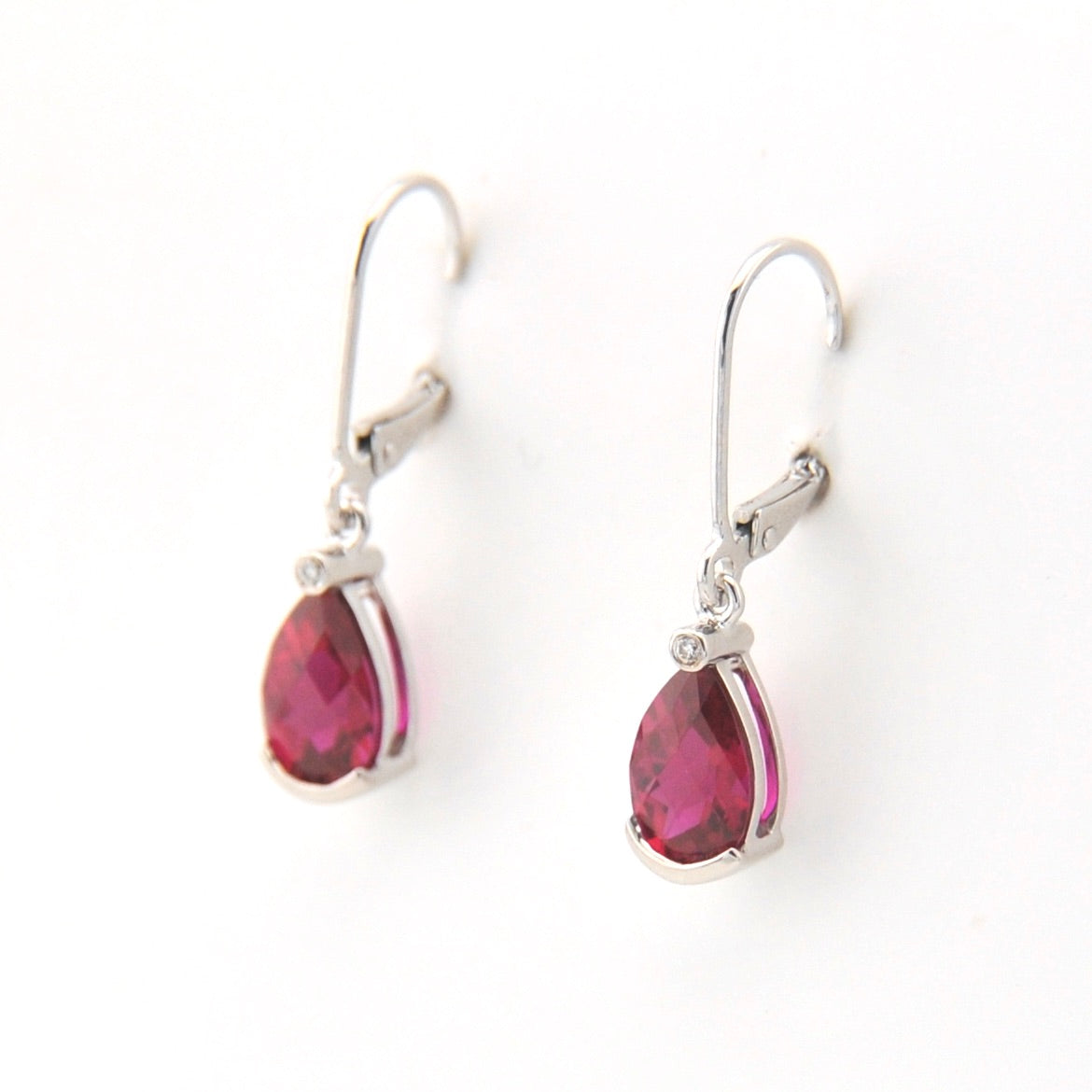 Pair of earrings with pink teardrop-shaped gemstones on a white background