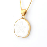 Gold necklace with a white circular pendant on a white background