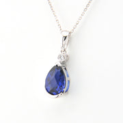 Silver necklace with a blue teardrop pendant on a white background