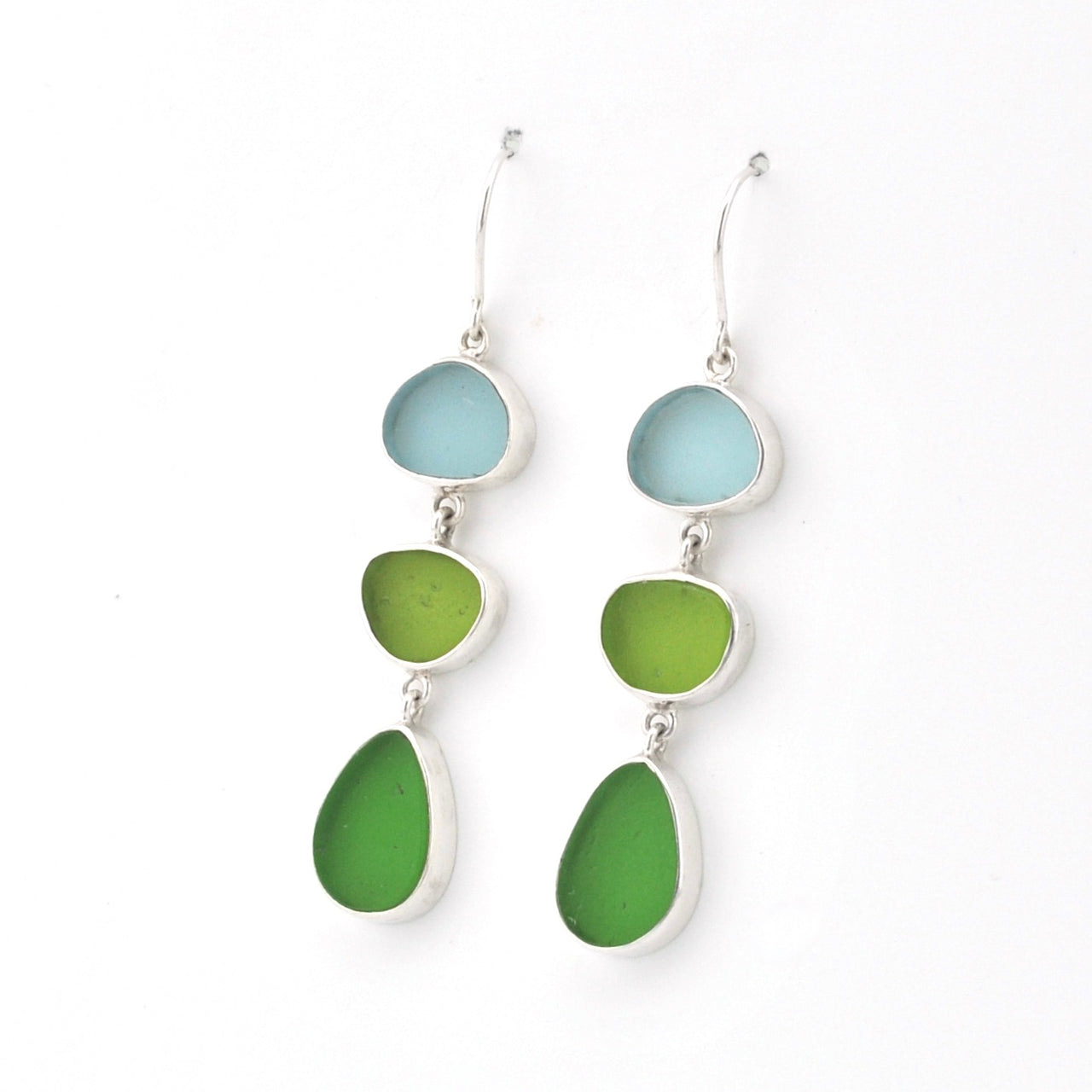 A pair of silver drop earrings featuring three stacked, irregularly shaped sea glass pieces in light blue, lime green, and medium green, shown against a plain white background.