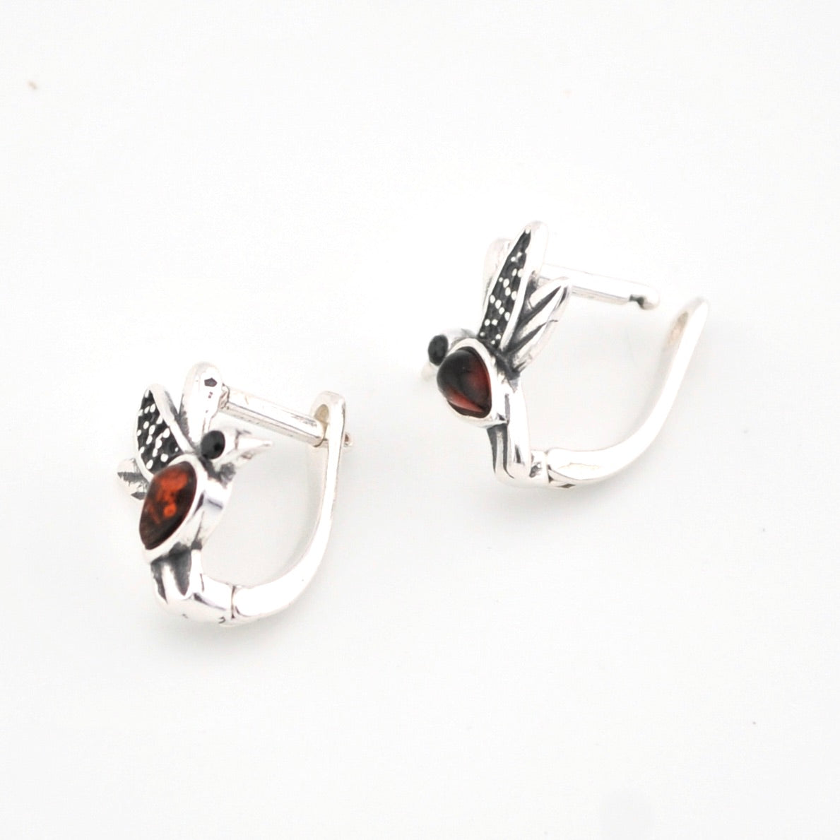 Pair of silver hoop earrings with red gemstones on a white background