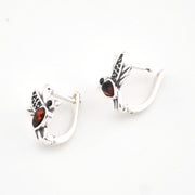 Pair of silver hoop earrings with red gemstones on a white background