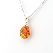 Amber teardrop pendant on a silver chain against a white background