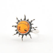 Silver sun-shaped pendant with amber center on a white background