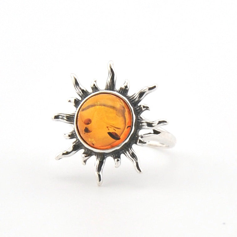 Silver sun-shaped pendant with amber center on a white background