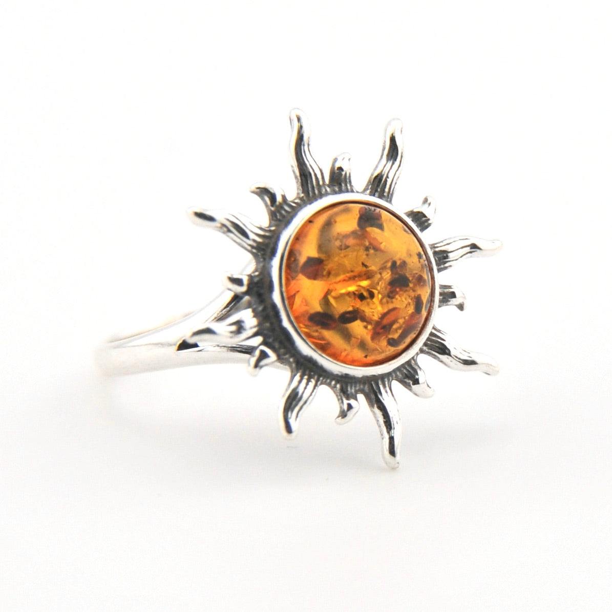 Silver ring with a sun design and amber stone on a white background